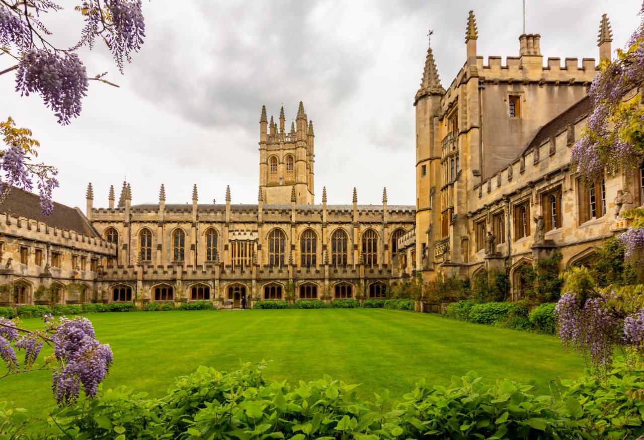 Where Was Young Sherlock Filmed? Visit the Real Locations From the Prime Hit Series- Oxford University college courtyard with Gothic architecture, green lawn, and flowering wisteria